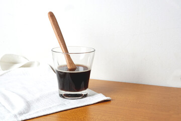 A glass of black coffee with wood spoon