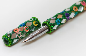 Handle decorated with mirrors and coloured beads on a white background