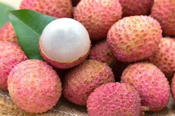 Pile of fresh lychee sweet fruit and peeled showing white fleshon on hemp sacks, Tropical fruits in thailand.