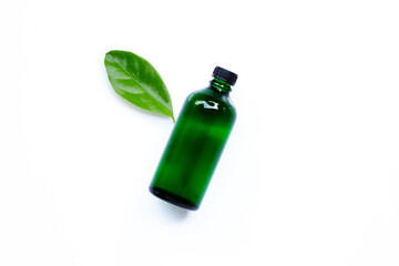 Essential oil bottle with green leaf on white background.