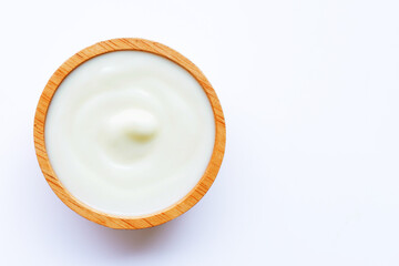 White yogurt in wooden bowl on white background.