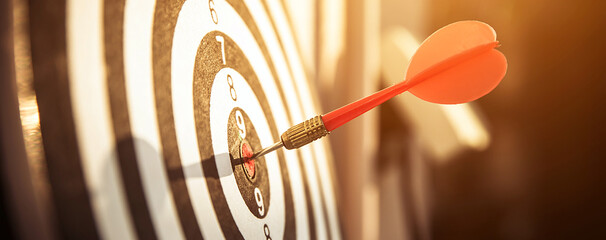 Bullseye or dart board has dart arrow throw hitting the center of a shooting target for business targeting and winning goals business concepts.