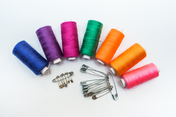 A set of colored threads on a spool "rainbow" with pins on a white background