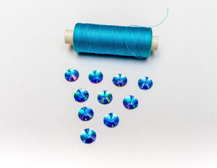Fototapeta na wymiar The coil of blue threads and blue sequins closeup on white background