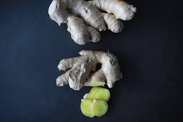 Ginger root whole and sliced. Ginger tea with lemon on the dark background. Fresh ginger root on...