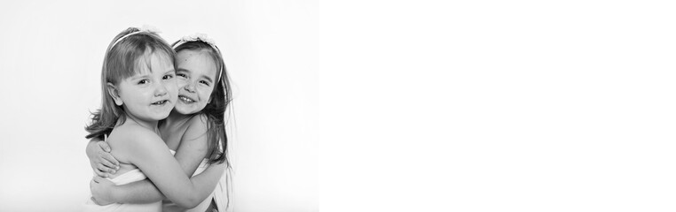 two little happy girls smiling on white background. Portrait of children hugging. The concept of relationships in the family, friends, sisters, couple in love. Copy space