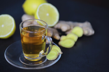 Ginger root whole and sliced. Ginger tea with lemon on the dark background. Fresh ginger root on stone background. Vitamins. Free space for your text.