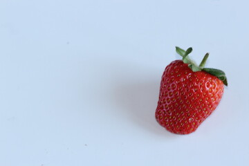 Fresa madura de color rojo sobre fondo azul