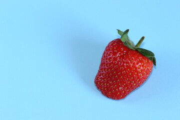 Fresa madura de color rojo sobre fondo azul
