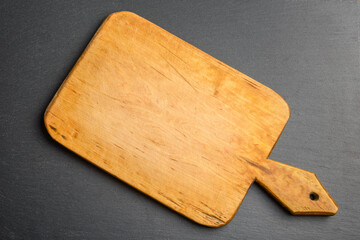 Empty vintage wooden cutting board on dark stone background