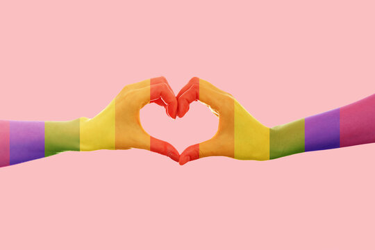 LGBT. Two females hands, painted in the colors of the rainbow flag, show the heart sign with their fingers. Pink background. Copy space. The concept of the LGBT movement and gay day