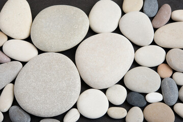 Top view of arranged pebble stones on black background