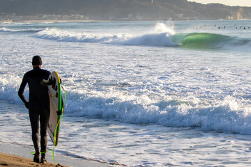 Surfing in Japan, man riding a surfboard in the pacific ocean near Tokyo