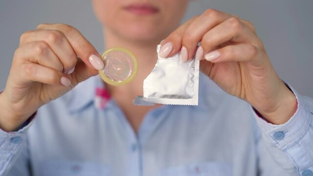 Female hands demonstrating condom before camera, safe sex, contraception