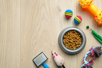 Fototapeta na wymiar Pet care and training concept. Flat lay composition with bowl of dry food and pet accessories on wooden table.