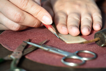 Obraz premium The tailor draws a sketch on leather material with a pencil and a ruler close up.