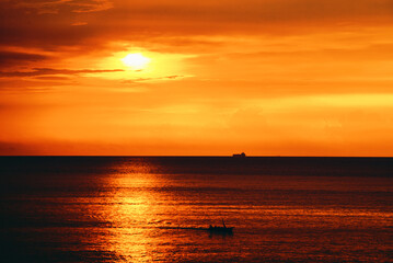 Naklejka na ściany i meble Silhouette boat in the ocean at sunset