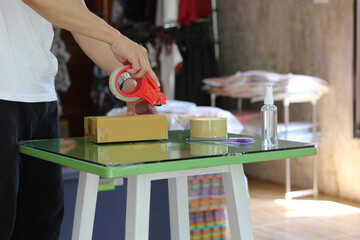 Thai man is packing post box in the shop , Tape, cutter