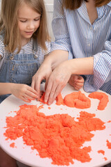 mom and daughter molded of red kinetic sand the word love.