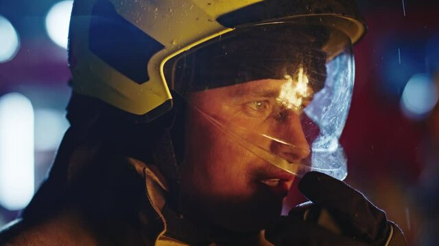 Portrait shot of a fireman in action speaking on the walkie talkie. Fire reflection on the helmet.