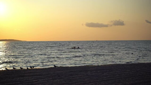 Silhouette of kayak with people are floating on it at dramatic sunset in Skane, Southern Sweden, Helsingborg