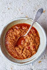 Italian meat stew bolognese in a bowl with spoon top view
