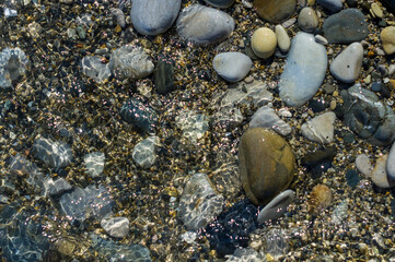pebble stones on the sea beach, the rolling waves of the sea with foam