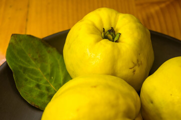 large yellow quince fruits on a ceramic plate, with anise, cinnamon, and walnuts