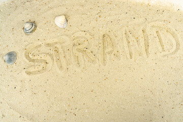 The German word for beach written in the sand of a beach