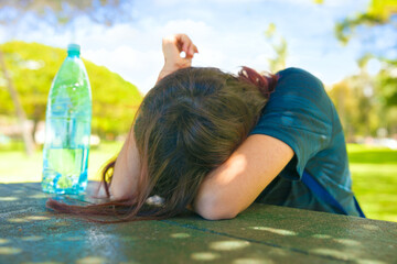 Teen girl head down on table on sunny day outdoors