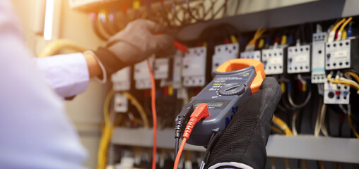 Electrical engineer using digital multi-meter to check current voltage at circuit breaker in main...