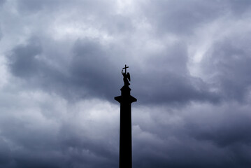 Angel with a cross on the background of storm clouds, the pillar of Alexandria