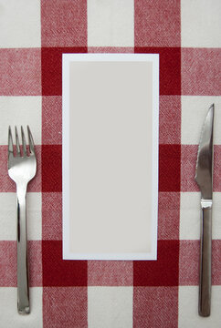 Mockup, Carta de menu en blanco para rellenar con cubiertos y un mantel de cuadros blancos y rojos.