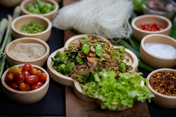 Raw rice flour in a wooden bowl with spices On a dark wood with natural light, focusing on the top of the noodles