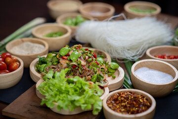 Raw rice flour in a wooden bowl with spices On a dark wood with natural light, focusing on the top of the noodles