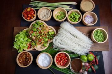 Raw rice flour in a wooden bowl with spices On a dark wood with natural light, focusing on the top...