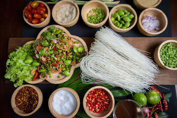 Raw rice flour in a wooden bowl with spices On a dark wood with natural light, focusing on the top of the noodles