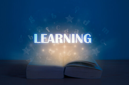 Learning concept. Light coming from open book. Open book with learning inscription.