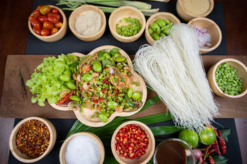 Raw rice flour in a wooden bowl with spices On a dark wood with natural light, focusing on the top of the noodles