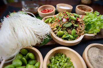 Raw rice flour in a wooden bowl with spices On a dark wood with natural light, focusing on the top...