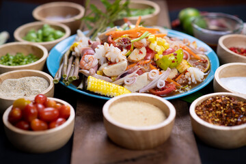 Raw rice flour in a wooden bowl with spices On a dark wood with natural light, focusing on the top of the noodles
