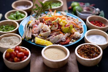 Raw rice flour in a wooden bowl with spices On a dark wood with natural light, focusing on the top of the noodles