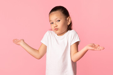 Confused puzzled asian girl shrugging at studio