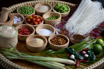 Raw rice flour in a wooden bowl with spices On a dark wood with natural light, focusing on the top of the noodles