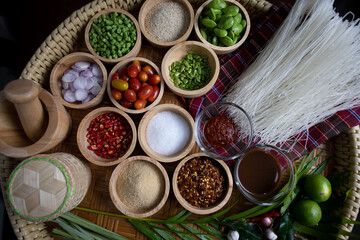 Raw rice flour in a wooden bowl with spices On a dark wood with natural light, focusing on the top of the noodles