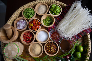 Raw rice flour in a wooden bowl with spices On a dark wood with natural light, focusing on the top of the noodles