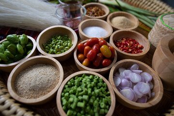 Raw rice flour in a wooden bowl with spices On a dark wood with natural light, focusing on the top of the noodles