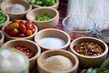Raw rice flour in a wooden bowl with spices On a dark wood with natural light, focusing on the top of the noodles