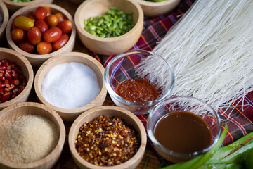 Raw rice flour in a wooden bowl with spices On a dark wood with natural light, focusing on the top of the noodles