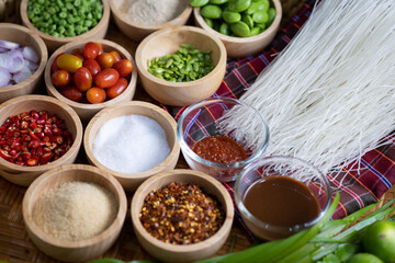 Raw rice flour in a wooden bowl with spices On a dark wood with natural light, focusing on the top of the noodles